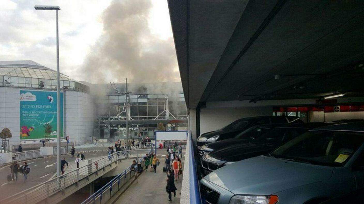 Denso fumo e gente in fuga escono dal terminal distrutto di Zaventem