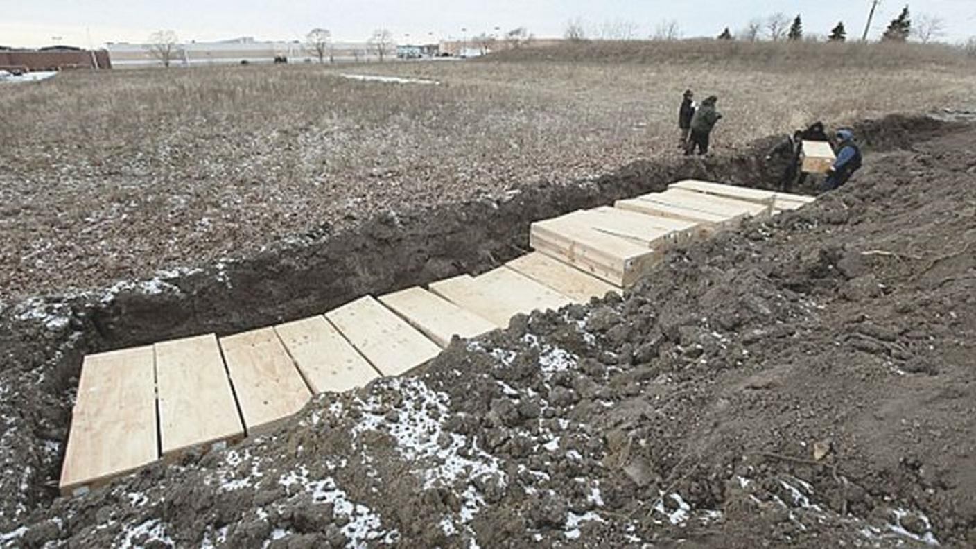Operai sistemano una fossa comune di Hart Island