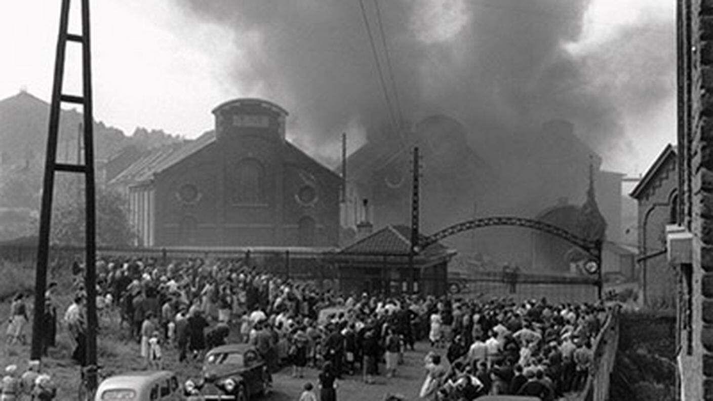 I parenti dei lavoratori accorrono ai cancelli della miniera in fiamme: l'immagine diventata simbolo della tragedia