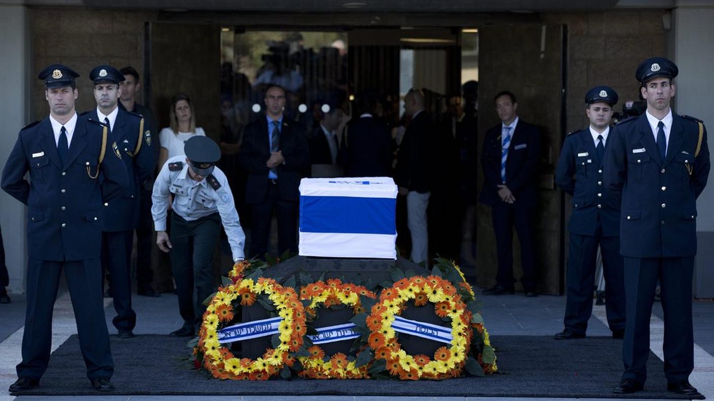 Le corone depositate accanto alla bara di Peres