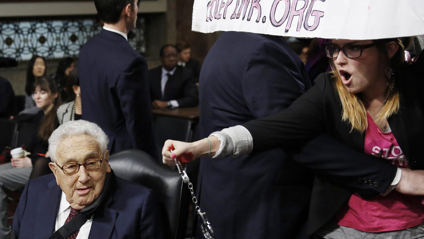 Un'immagine, emblematica, del 2015: Kissinger preso di mira a Washington da una contestatrice che, brandendo delle manette, lo apostrofò come criminale di guerra