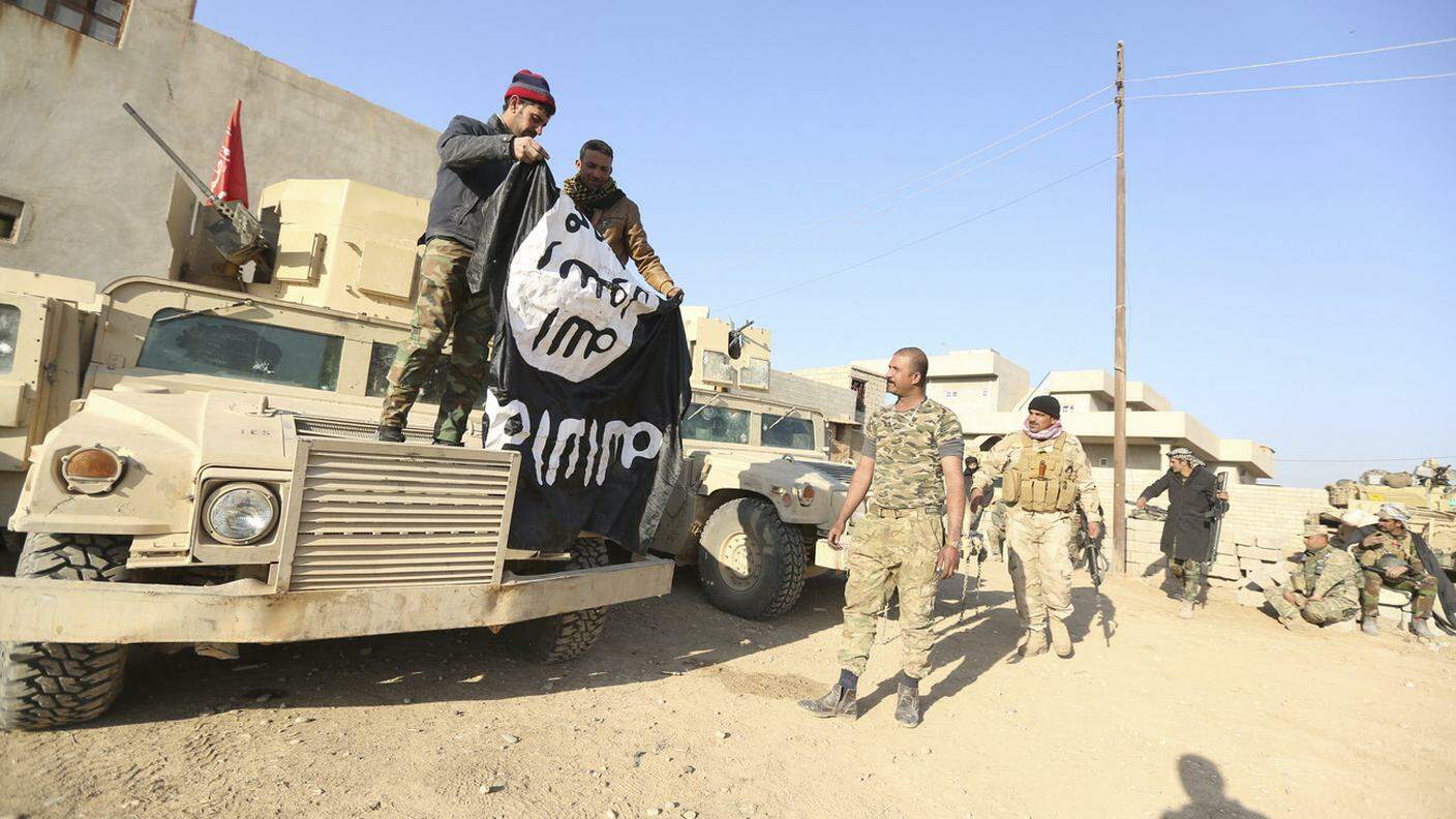 Una bandiera dell'IS mostrata da soldati iracheni, dopo il successo di un'operazione militare