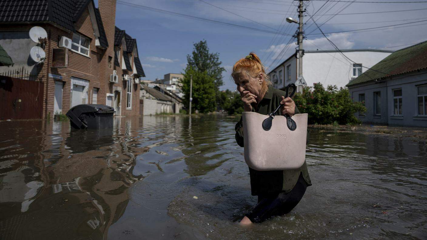 Una signora di Kherson attraversa sconvolta la strada inondata nel suo quartiere