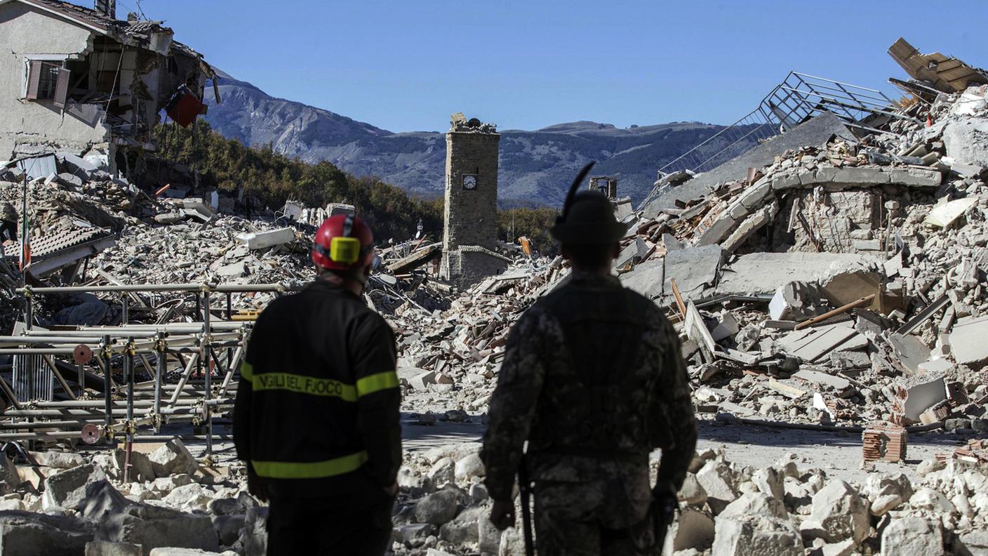 Un pompiere e un alpino di fronte alle macerie di Amatrice in uno scatto dell'ottobre 2016