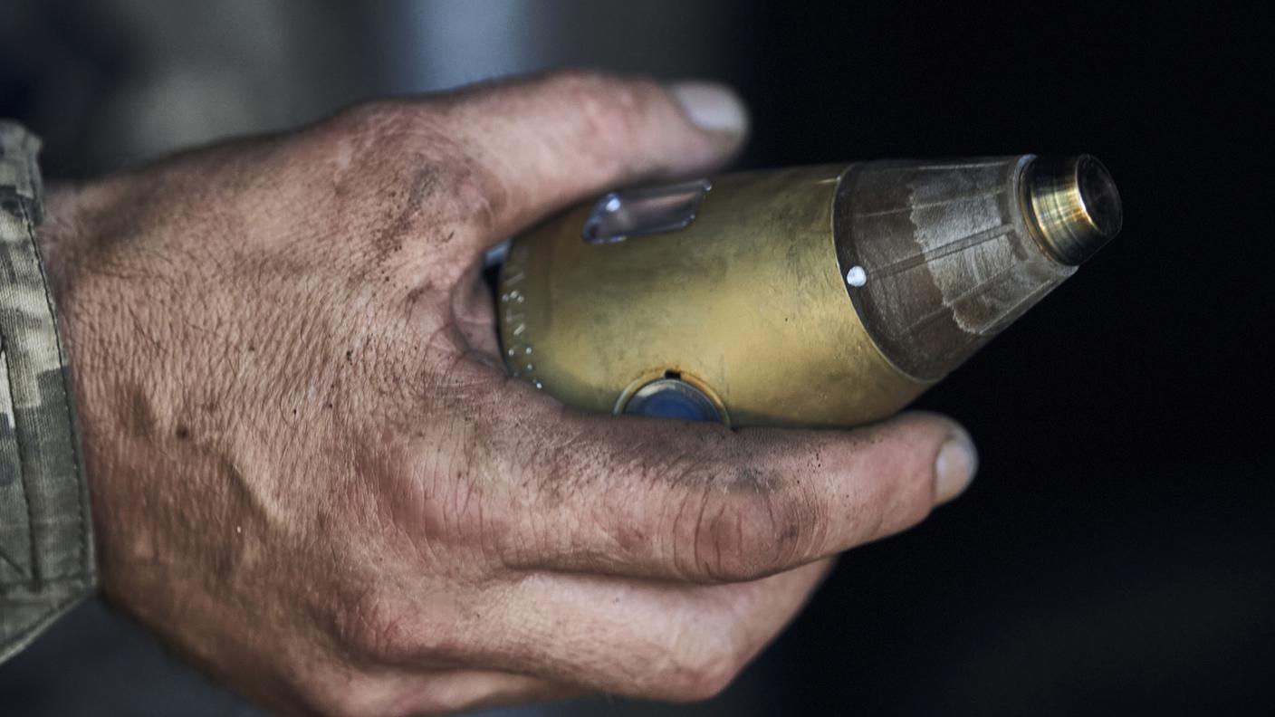 Un soldato ucraino tiene in mano la miccia di un proiettile di un obice