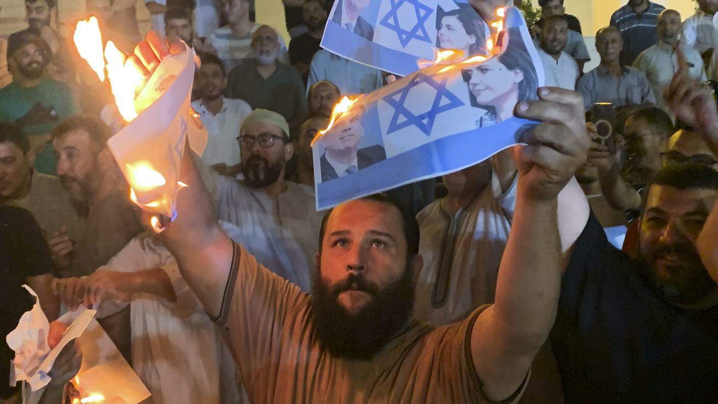 Manifestanti bruciano a Tripoli immagini con la bandiera di Israele e la foto dei due ministri degli esteri coinvolti nell'incontro