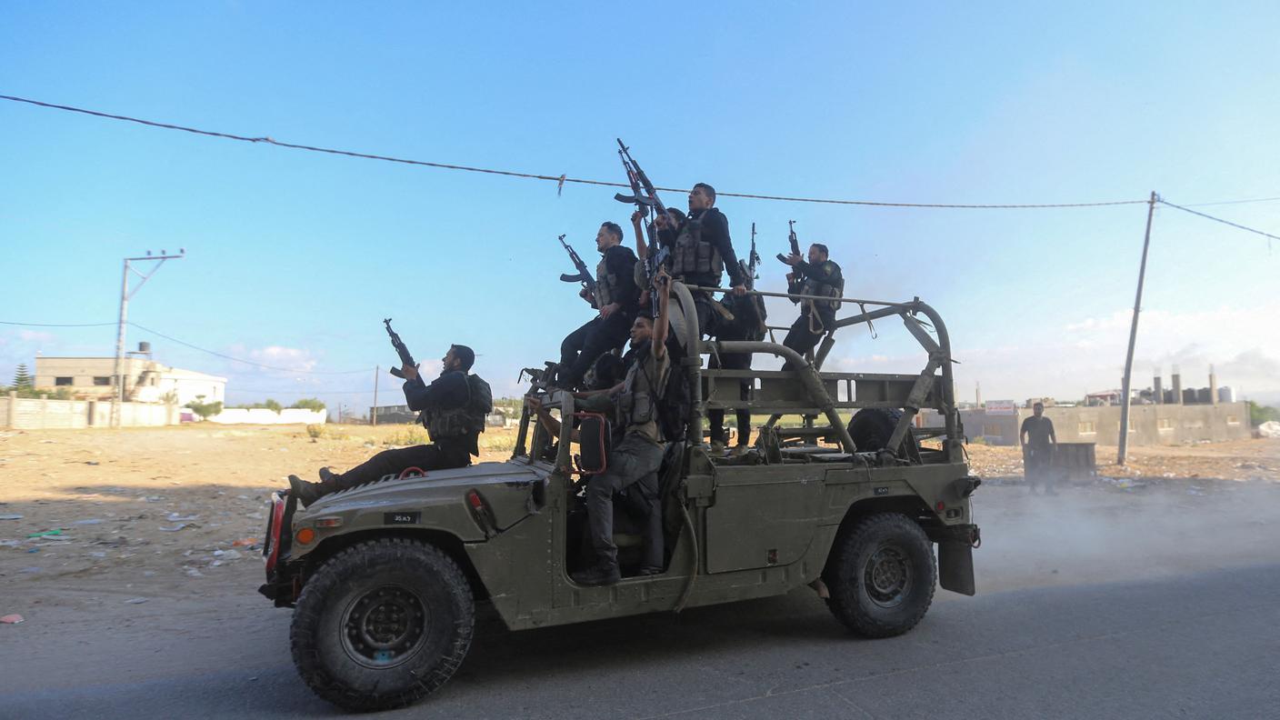 Miliziani palestinesi guidano un veicolo dell'esercito israeliano nel sud del Paese