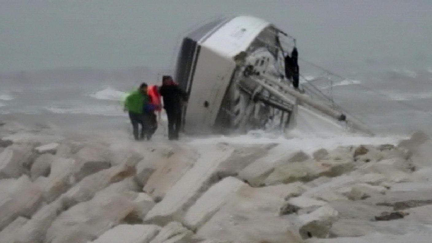 La barca a vela spinta sulla scogliera del porto dal mare in burrasca