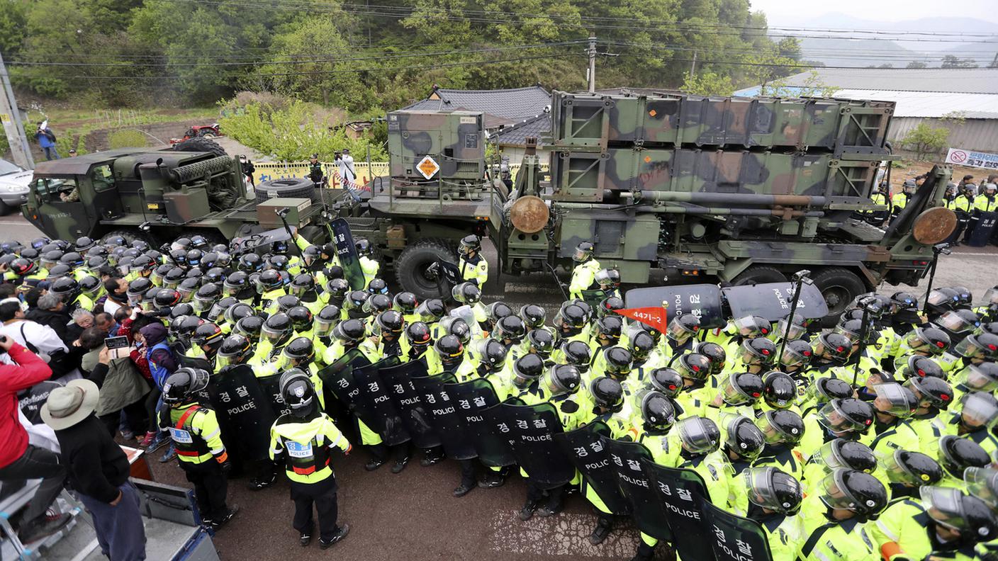 Agenti scortano i sistemi THAAD a Seongju, nella Corea del Sud, tra le proteste dei residenti