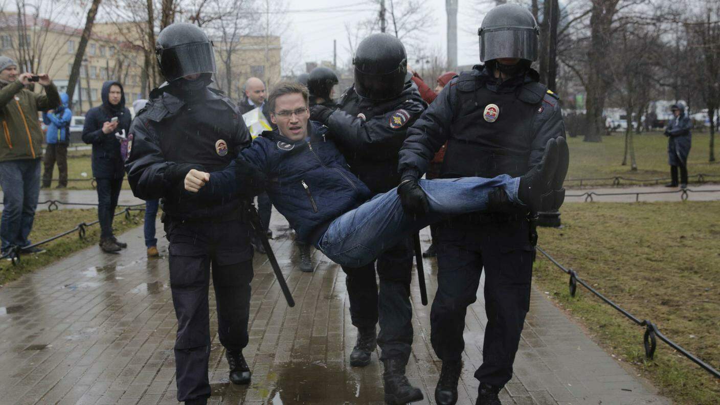 Un dimostrante portato via di peso dai poliziotti sabato a San Pietroburgo