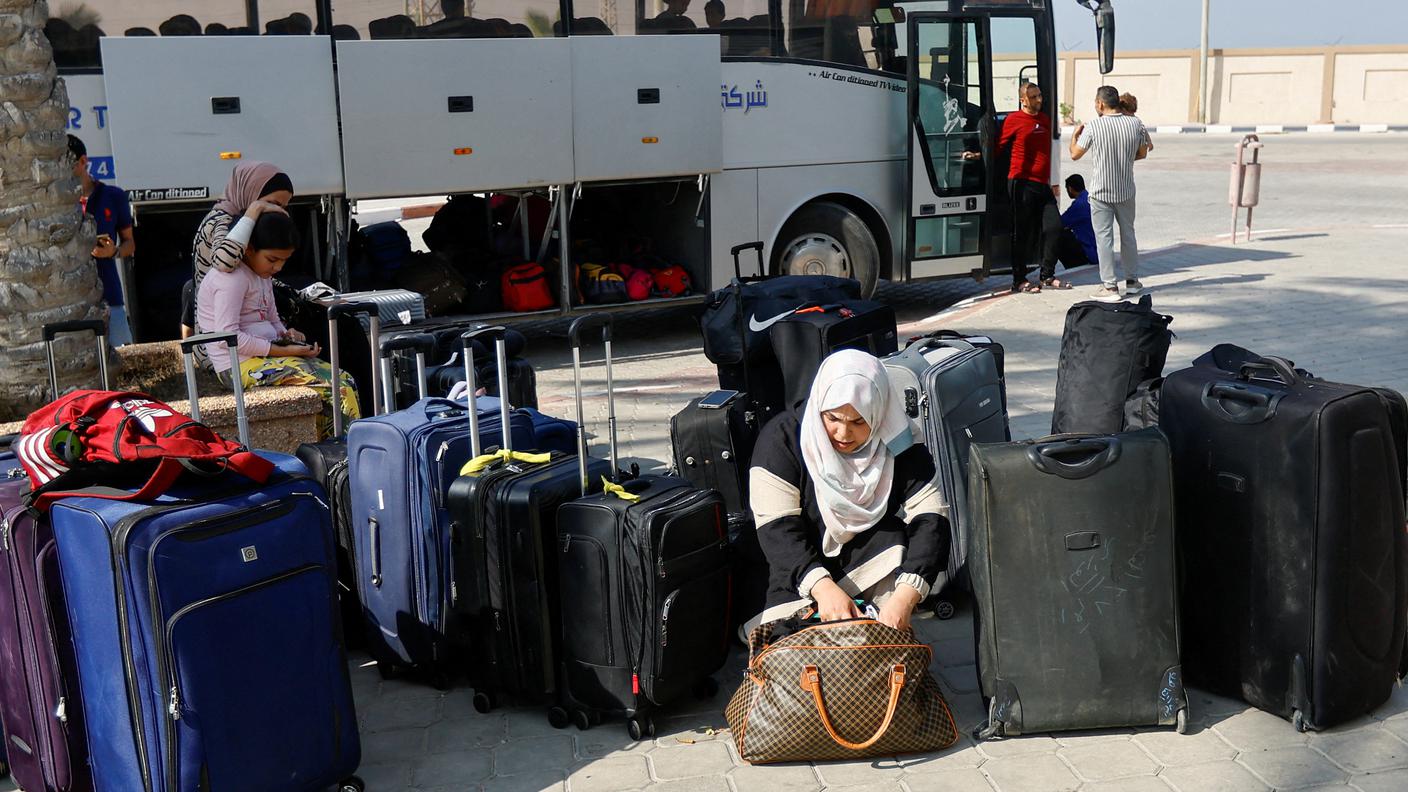 Un gruppo di cittadini palestinesi aspetta di lasciare Gaza davanti al valico di Rafah
