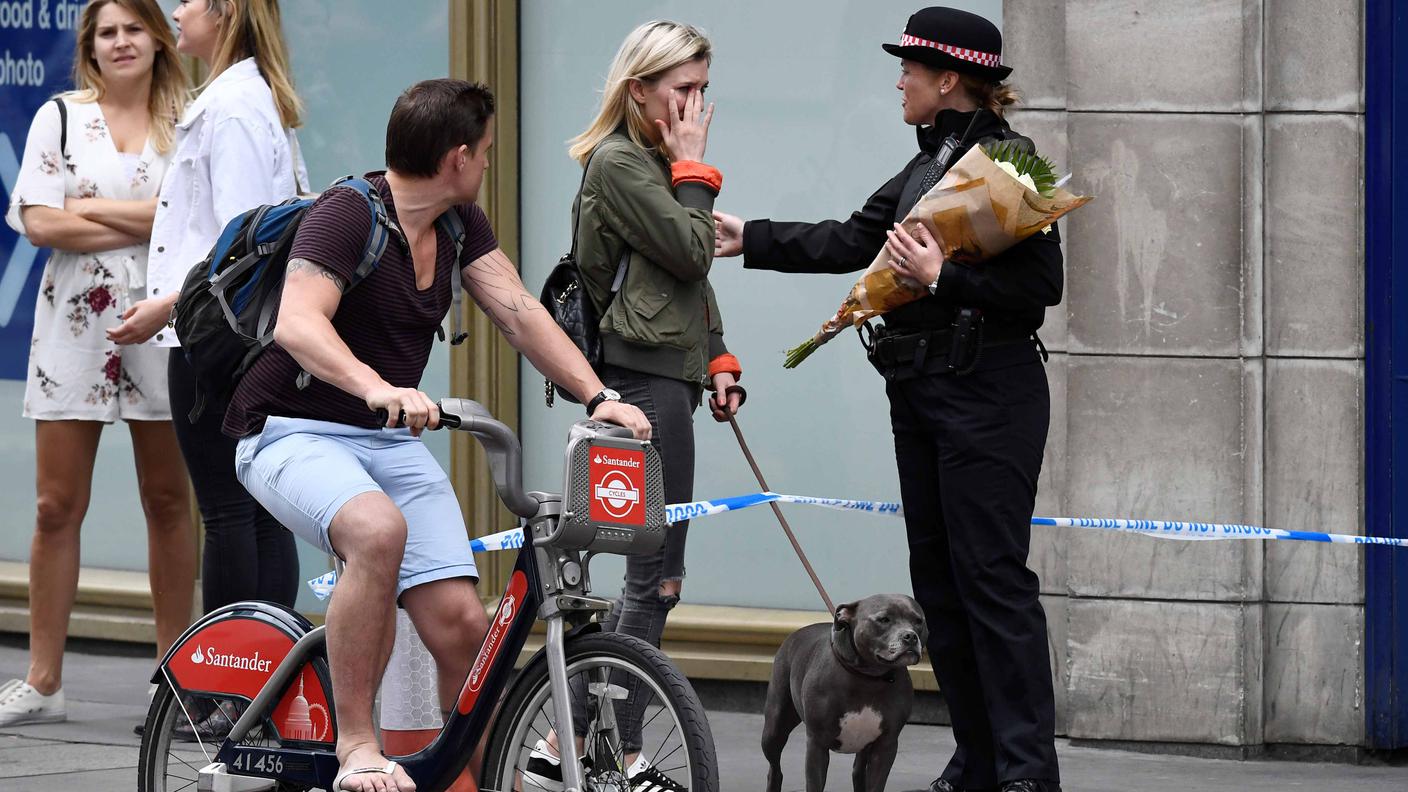 Una donna commossa lascia un mazzo di fiori ad un'agente presso il London Bridge