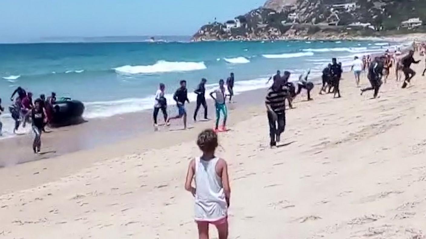 Una turista assiste a uno sbarco di migranti a Cadice