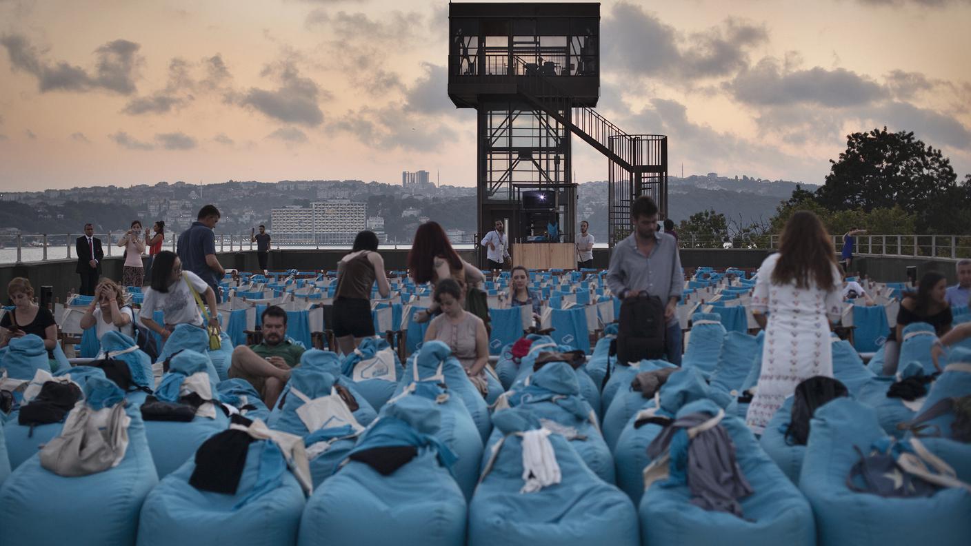 Sul tetto della fabbrica è stato allestito un cinema all’aperto. Gli spettatori prendono posto,prima di una proiezione.