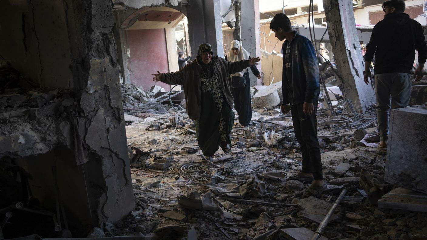 Palestinesi in mezzo alla distruzione dopo un attacco israeliano a Rafah