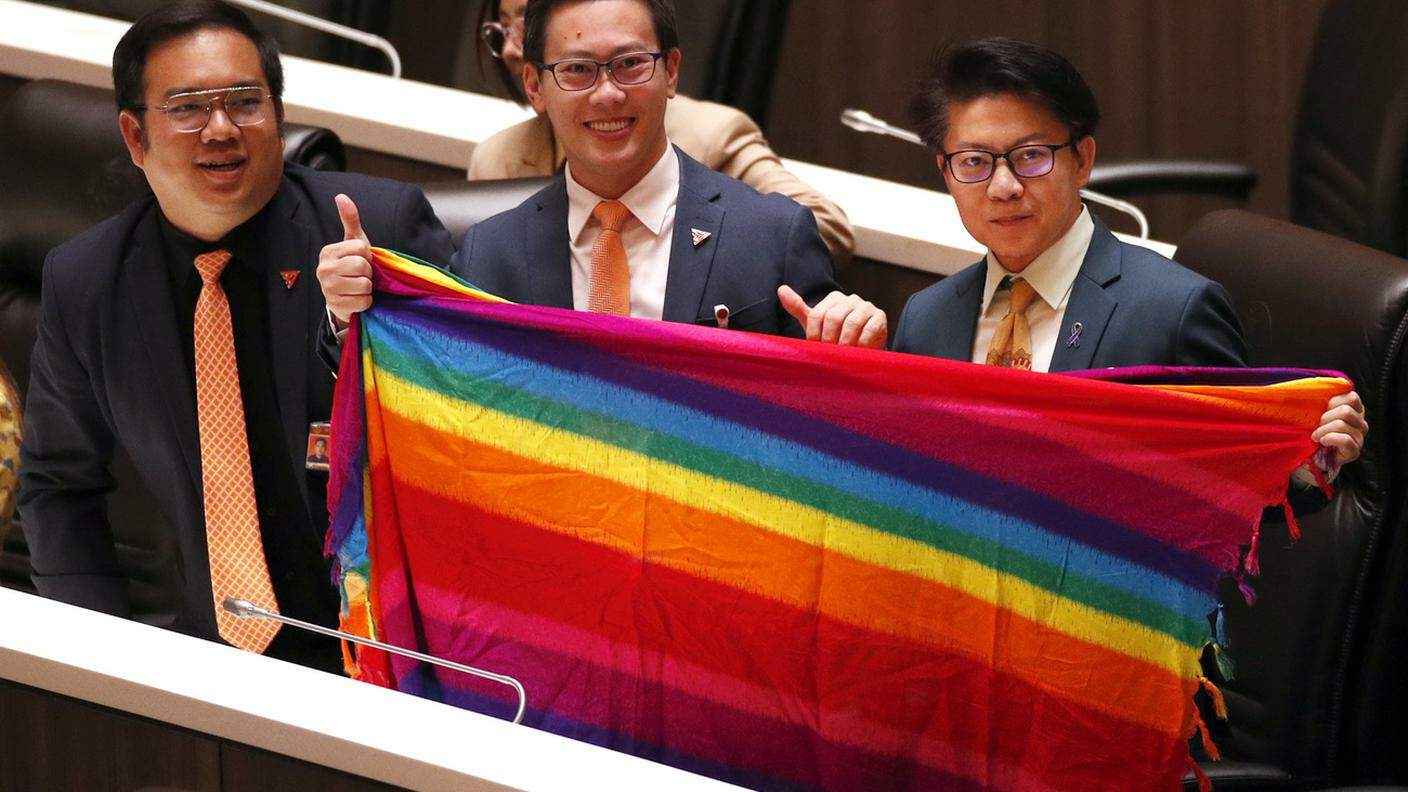 Deputati del Parlamento thailandese con una bandiera arcobaleno