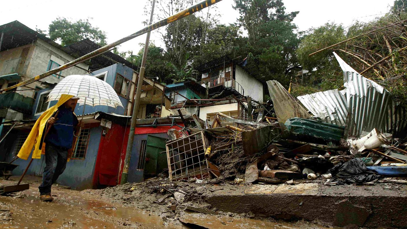 Un uomo passeggia nel fango accanto a case distrutte da Nate in Costa Rica