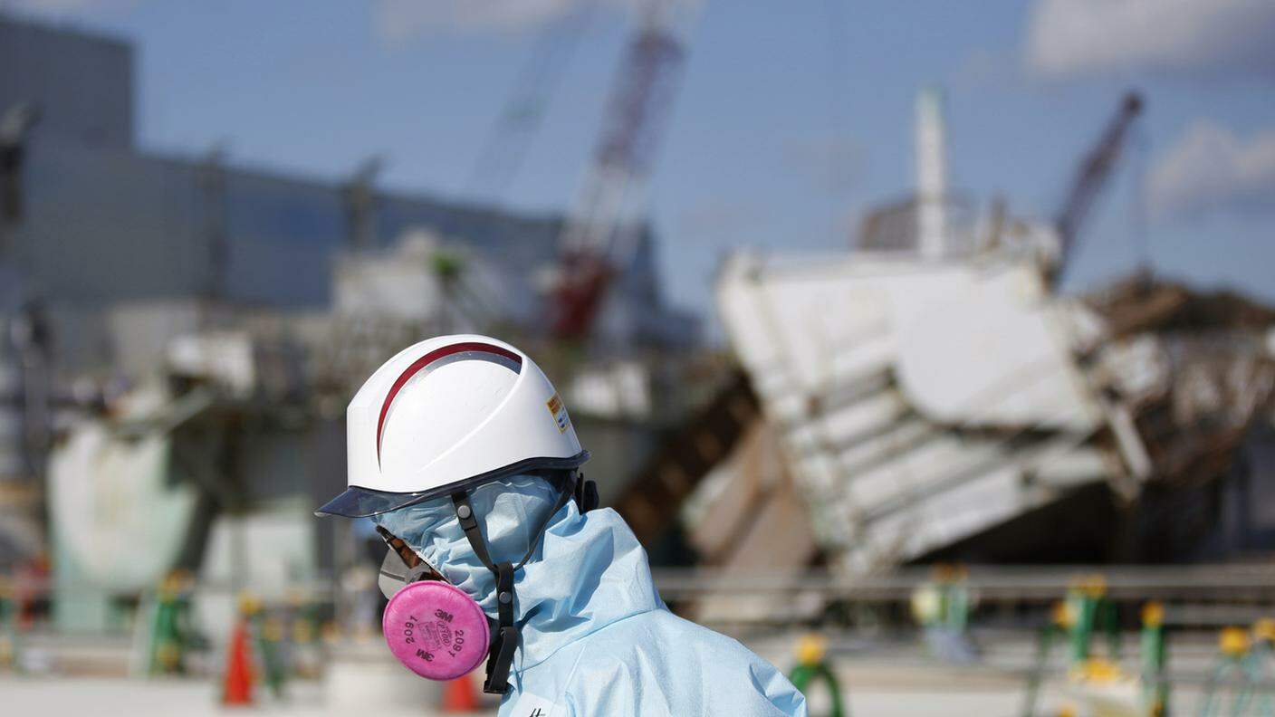 Un operatore davanti al reattore danneggiato della centrale nucleare di Fukushima