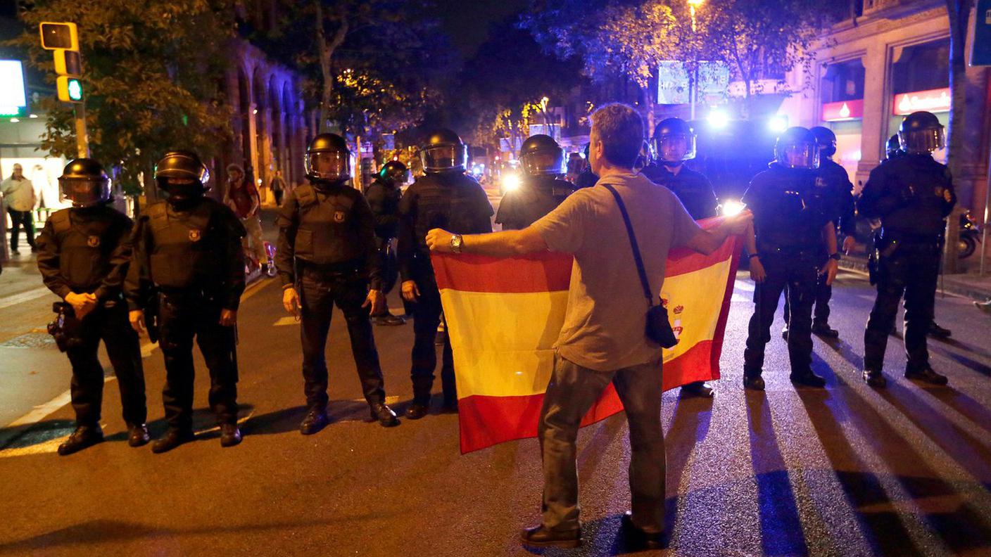 Un manifestante unionista mostra la bandiera spagnola di fronte agli agenti a Barcellona