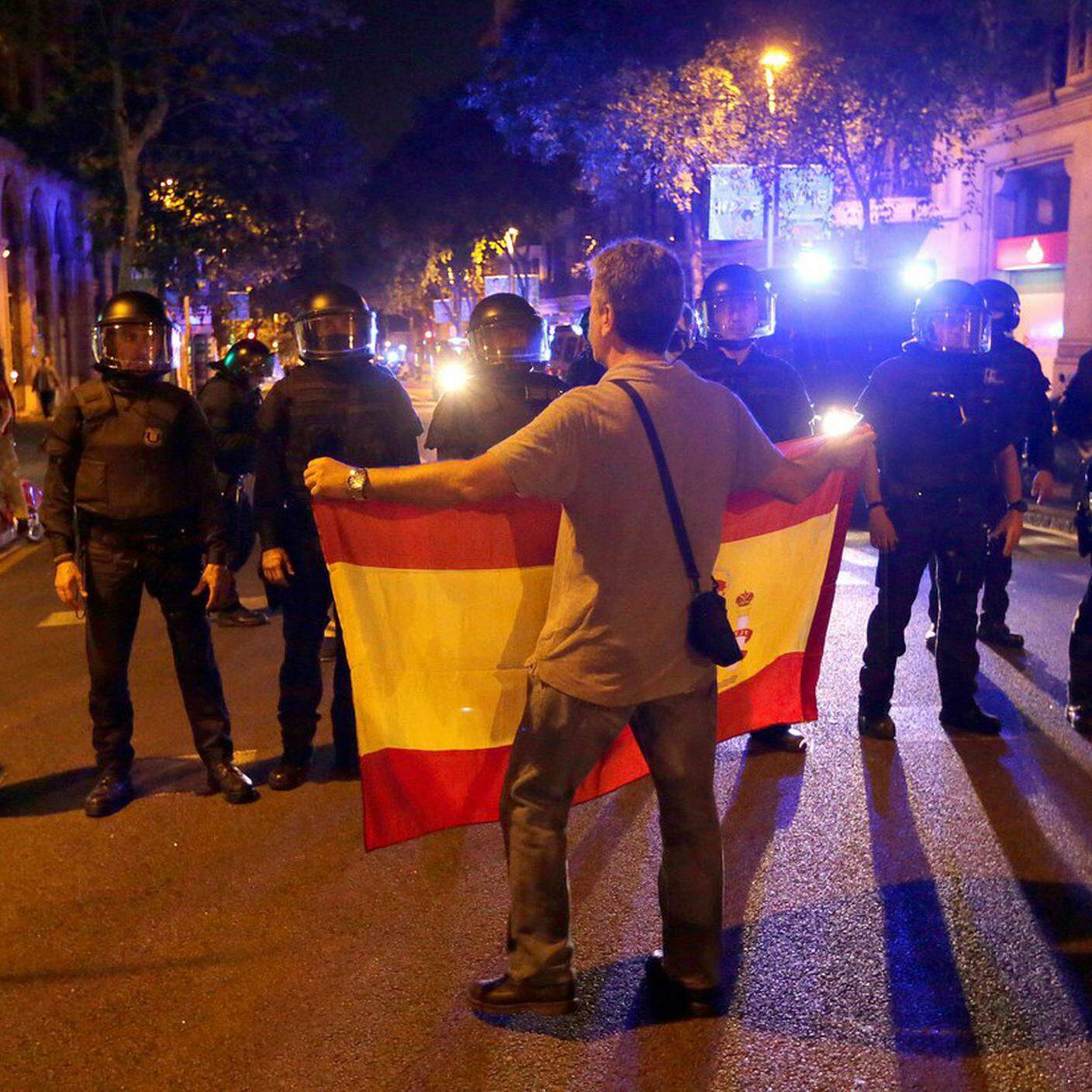 Un manifestante unionista mostra la bandiera spagnola di fronte agli agenti a Barcellona
