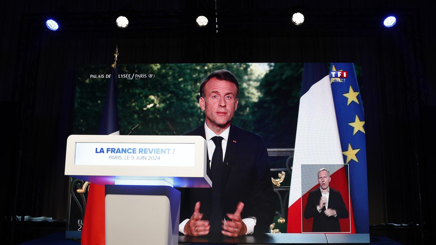 L'annuncio in tv di Macron scorre sullo schermo al raduno del RN. jpg