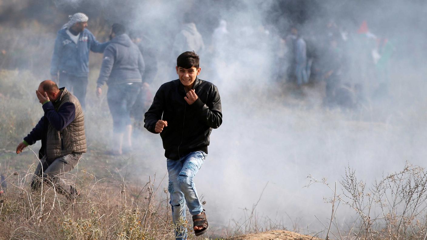 Alcuni giovani fuggono dal gas lacrimogeno scagliato dai soldati israeliani a Gaza