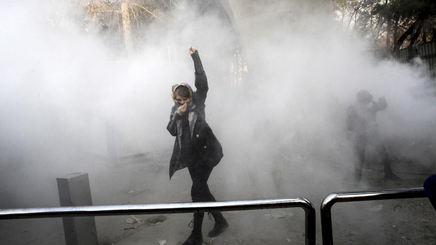 Una dimostrante protesta in una nuvola di gas lacrimogeno a Teheran