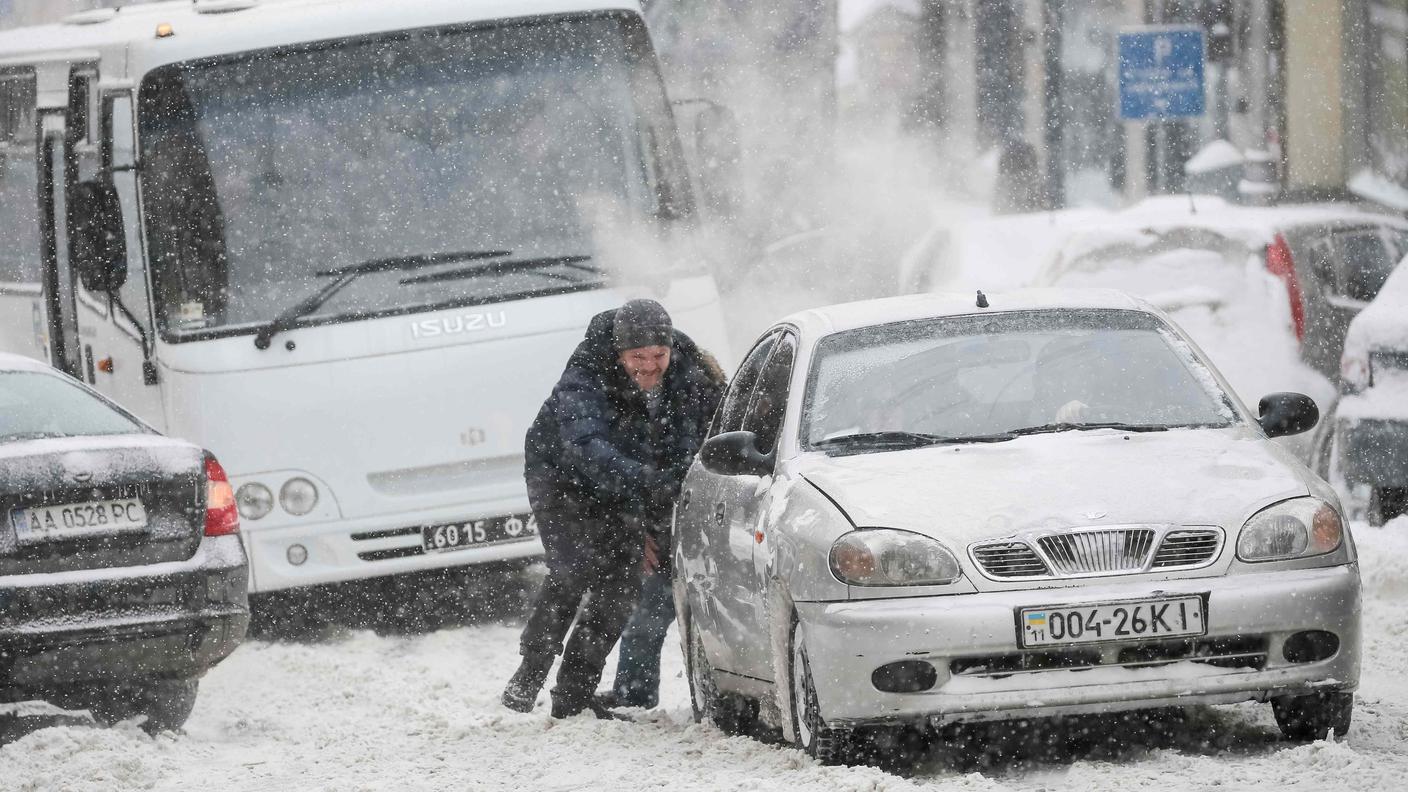 Si spinge un'auto bloccata dalla neve nel centro di Kiev giovedì