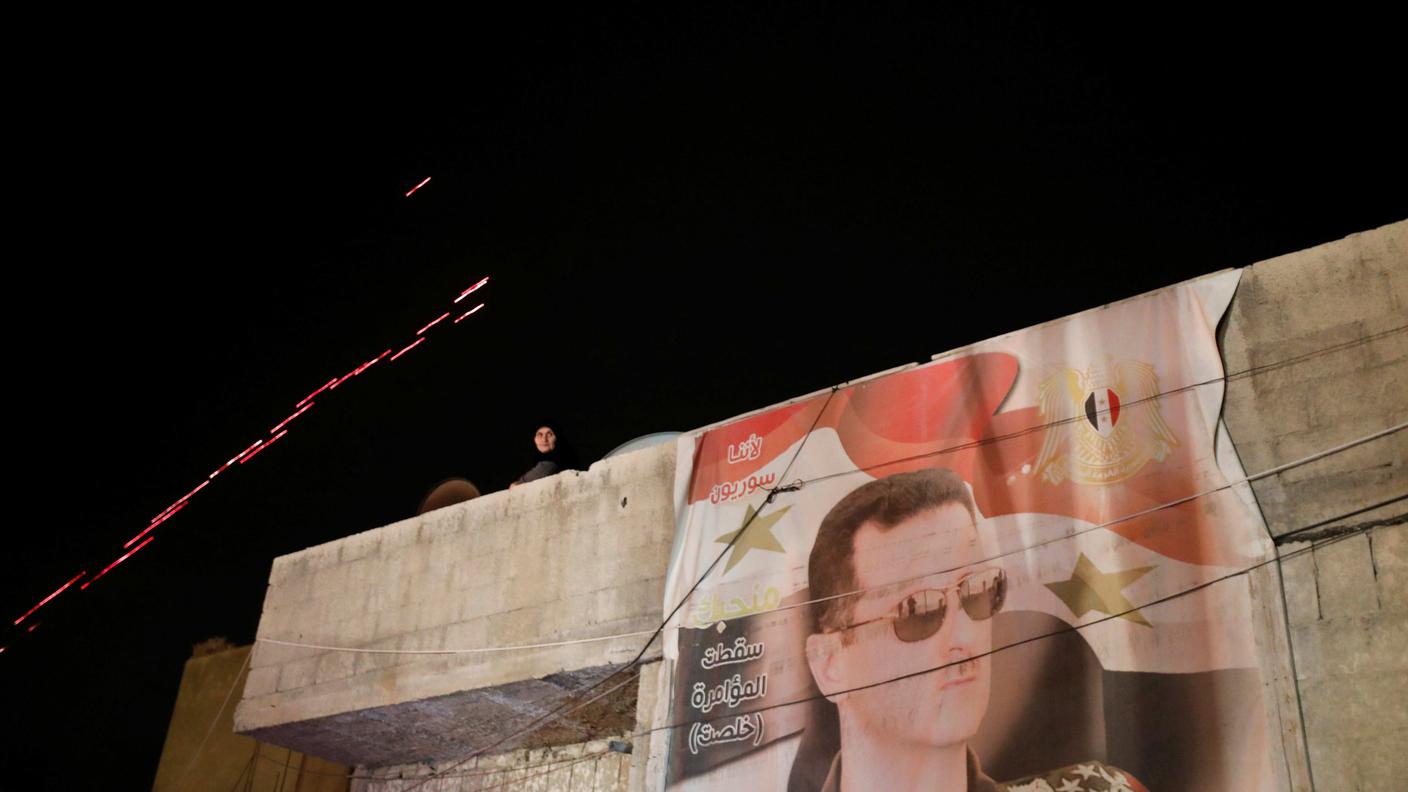 Una bandiera siriana con l'effigie del presidente Assad su un muro di Duma