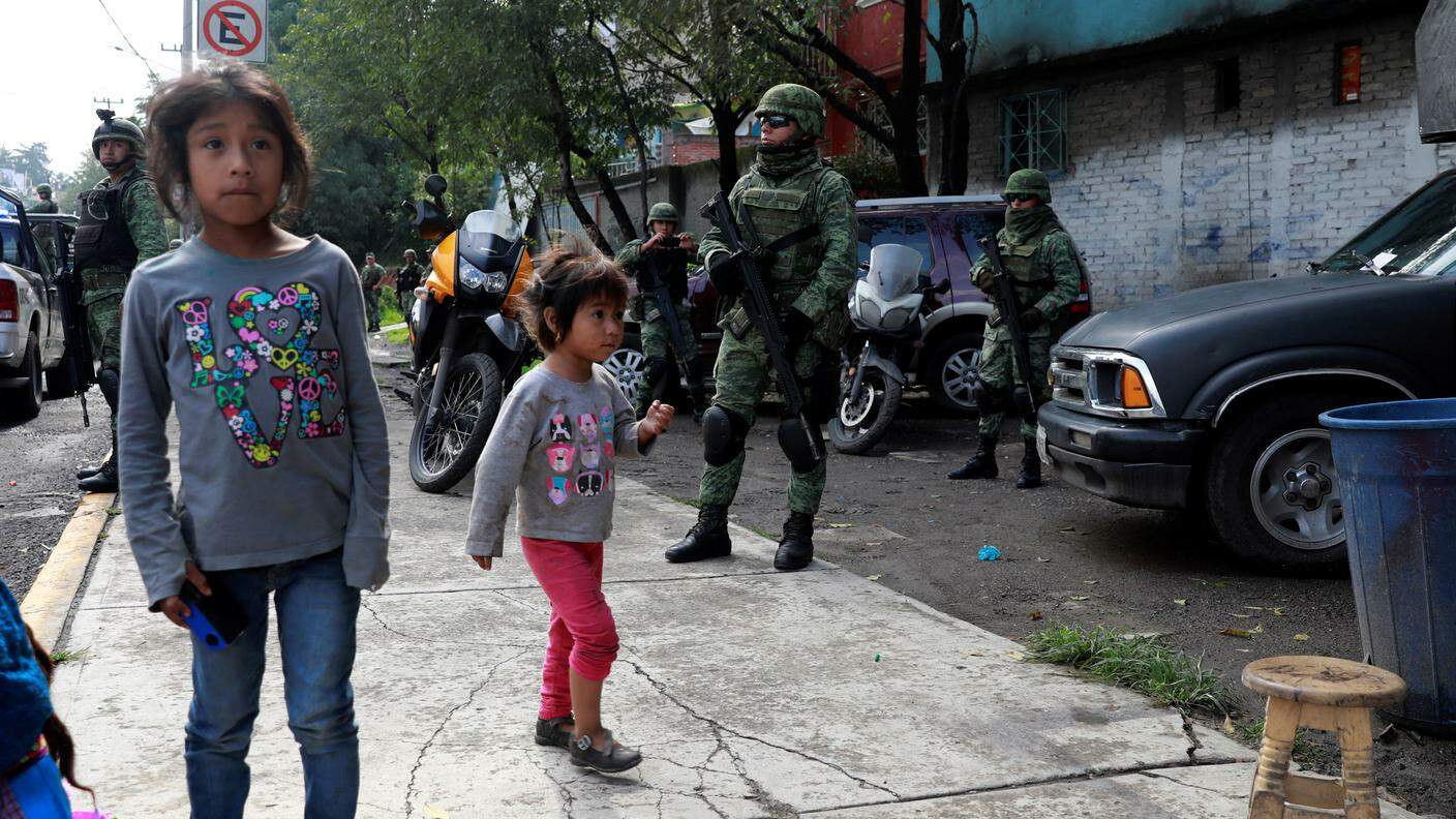 Bambini messicani giocano vicino a dei militari