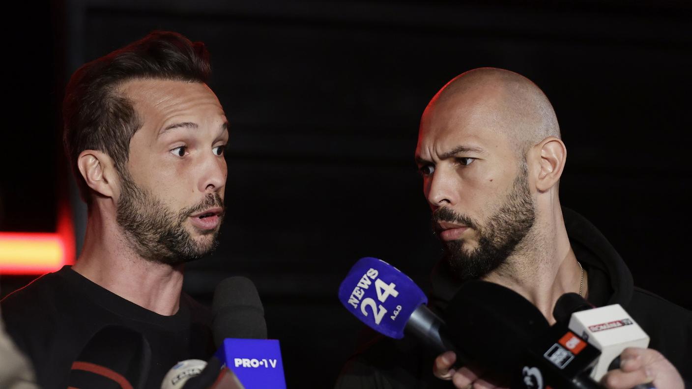 Andrew Tate (destra) e il fratello Tristan davanti ai giornalisti a Bucarest