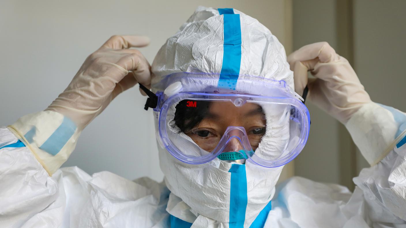 Un medico con guanti e tuta protettiva in un'ospedale di Wuhan, epicentro dell'epidemia