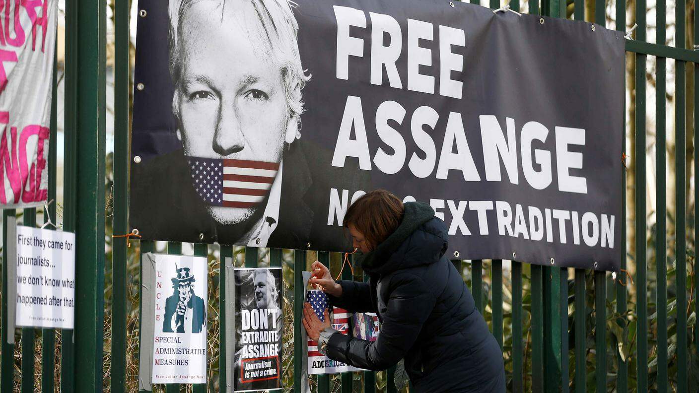 Una donna attacca un manifesto pro-Julian Assange davanti al Tribunale dove è processato