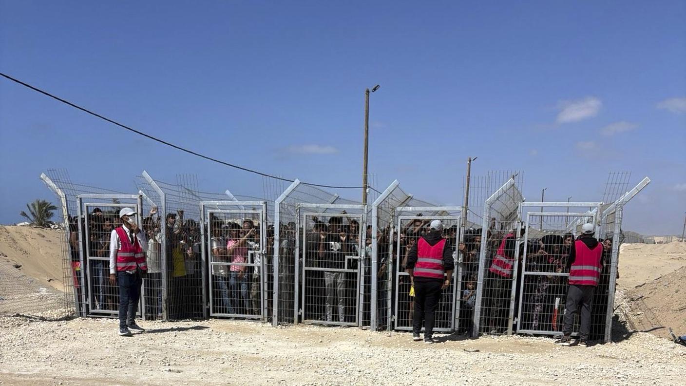 Palestinesi dietro i cancelli davanti a un sito di distribuzione di aiuti