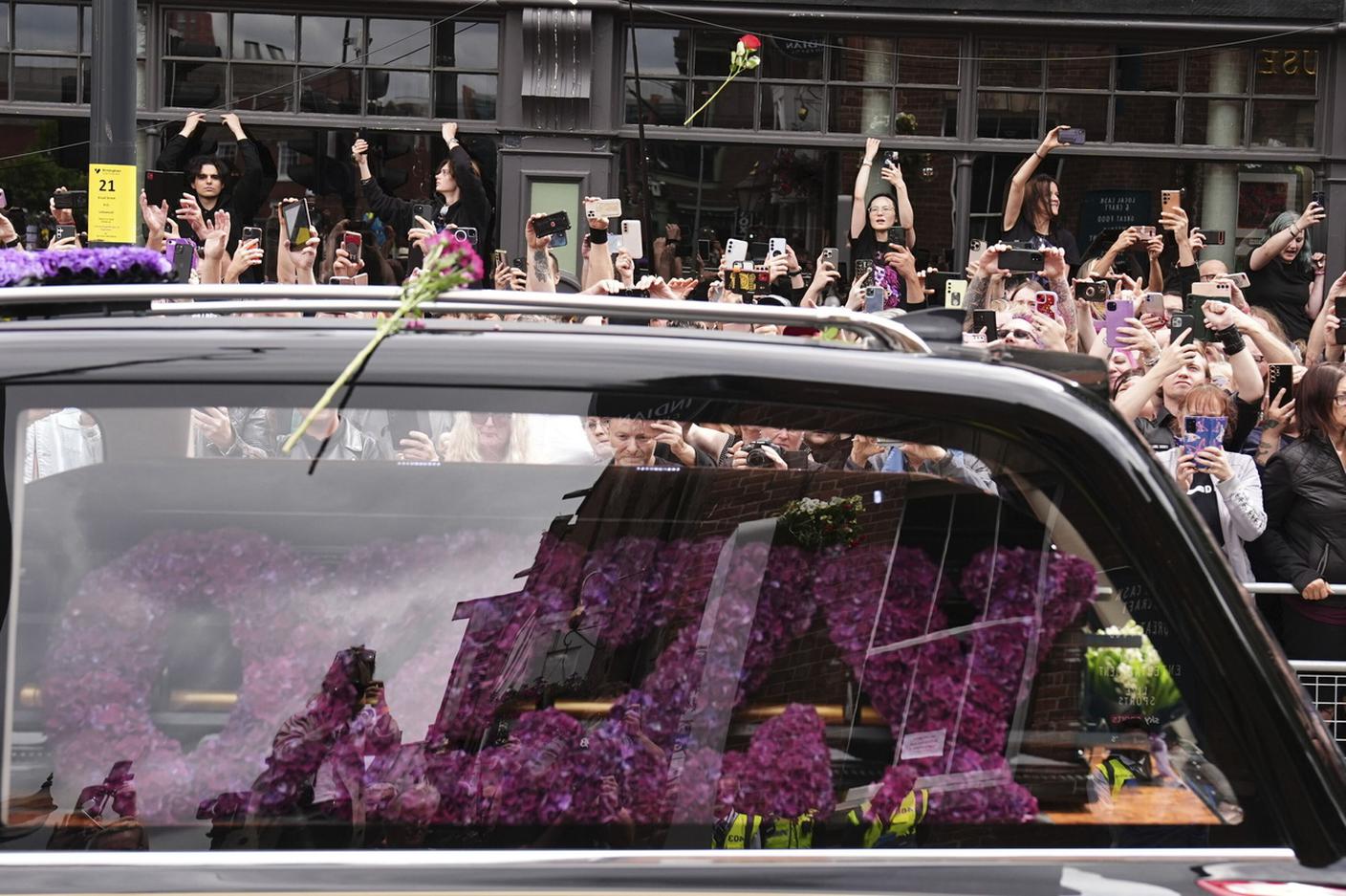 Una corona di fiori viola sul carro funebre.jpg