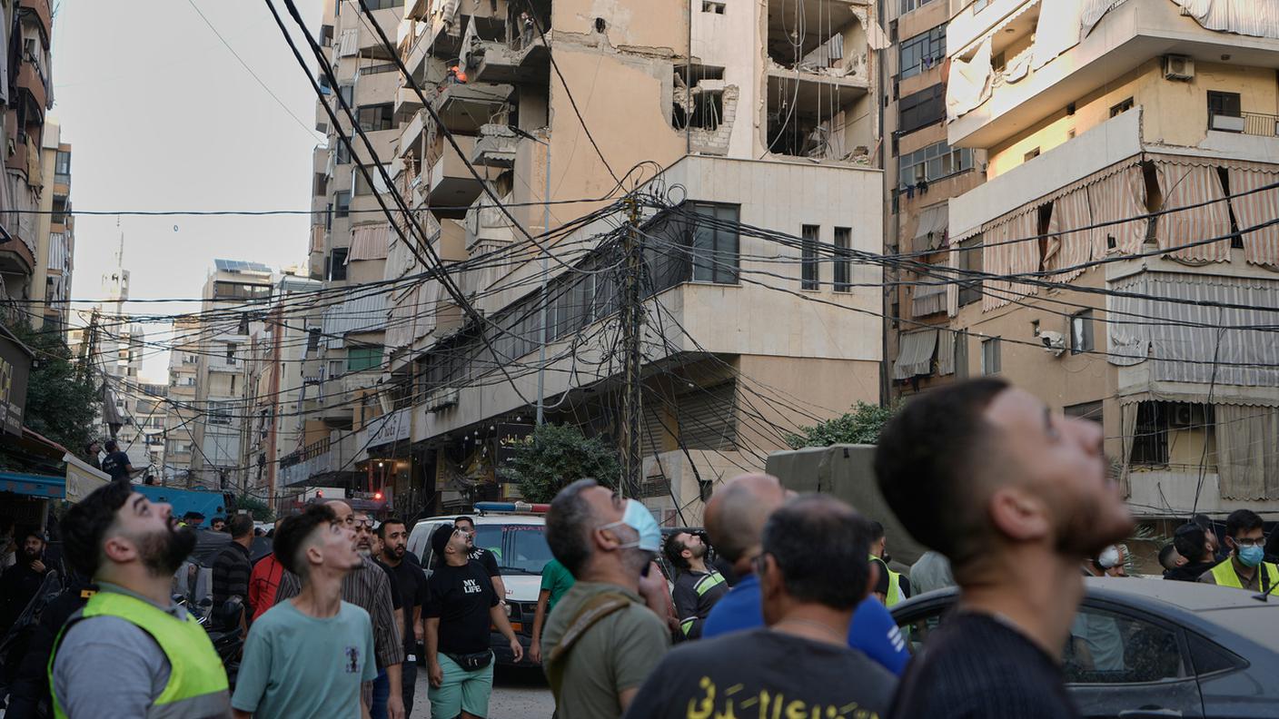 Civili osservano i palazzi colpiti dall'attacco israeliano a Dahiyeh