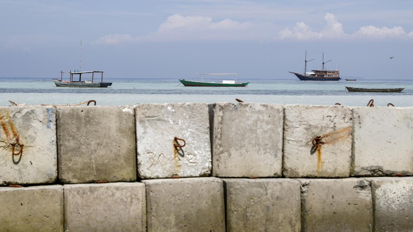Barche di pescatori ancorate su una spiaggia dell'isola di Pari dietro un frangiflutti in cemento