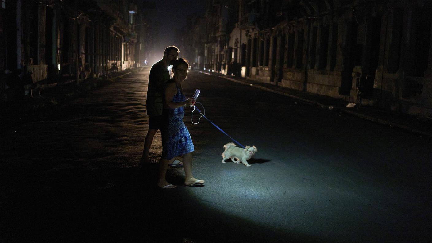 Una coppia porta a spasso il cane nel buio di uno dei tanti blackout che avvengono sull'isola di Cuba