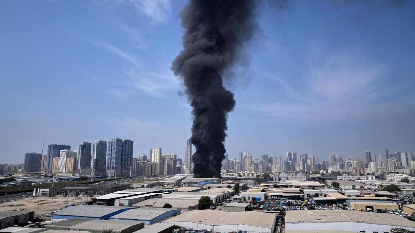 Una colonna nera di fumo si alza da un magazzino nella zona industriale della città di Sharjah negli Emirati Arabi Uniti