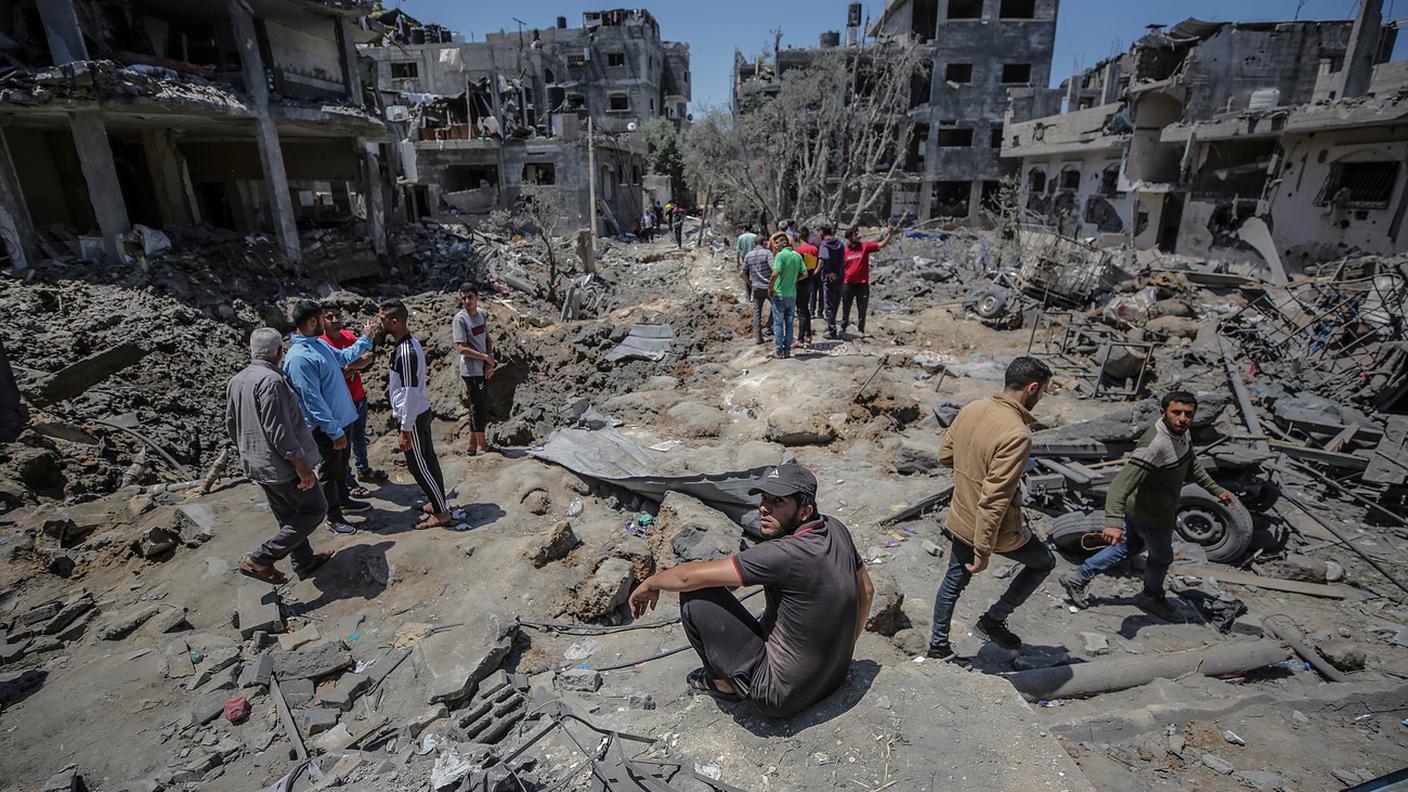 Palestinesi fra le macerie di un edificio colpito dai bombardamenti su Gaza