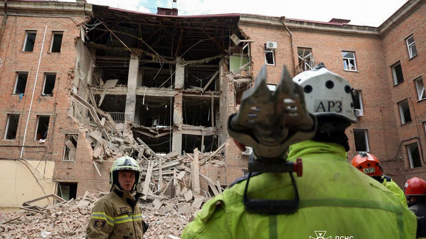 Soccorritori al lavoro davanti ad un immobile distrutto in un quartiere residenziale di Dnipro