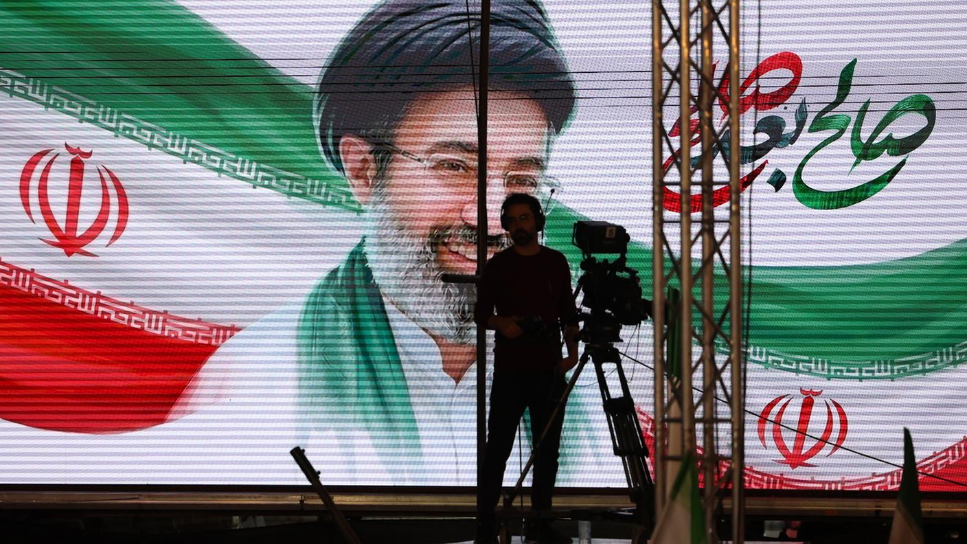 Un cameramen di fronte alla foto gigante dell'Ayatollah Mojtaba Khamenei 