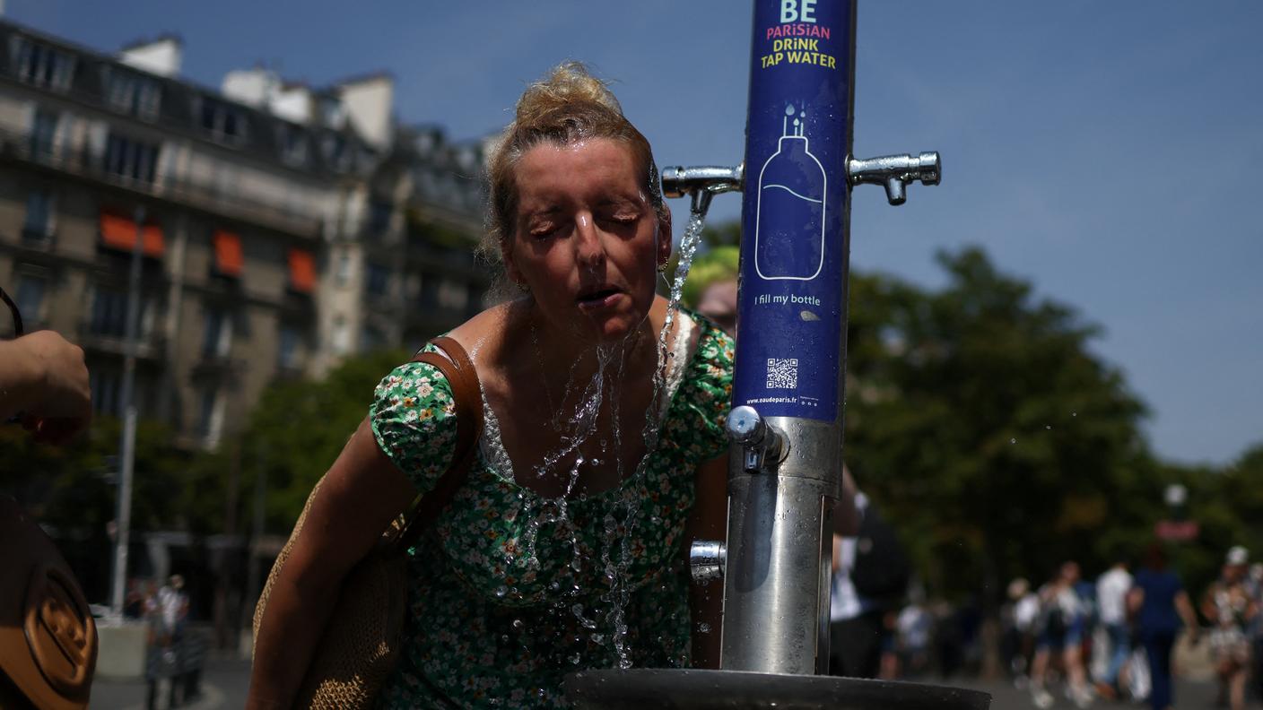 Una donna che tentava di rinfrescarsi a una fontanella del Trocadero di Parigi, sabato