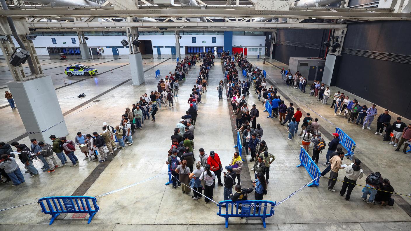 Persone in fila per ricevere i documenti in vista dell'avvio del processo di regolarizzazione di massa dei migranti in Spagna. La foto è dello scorso aprile
