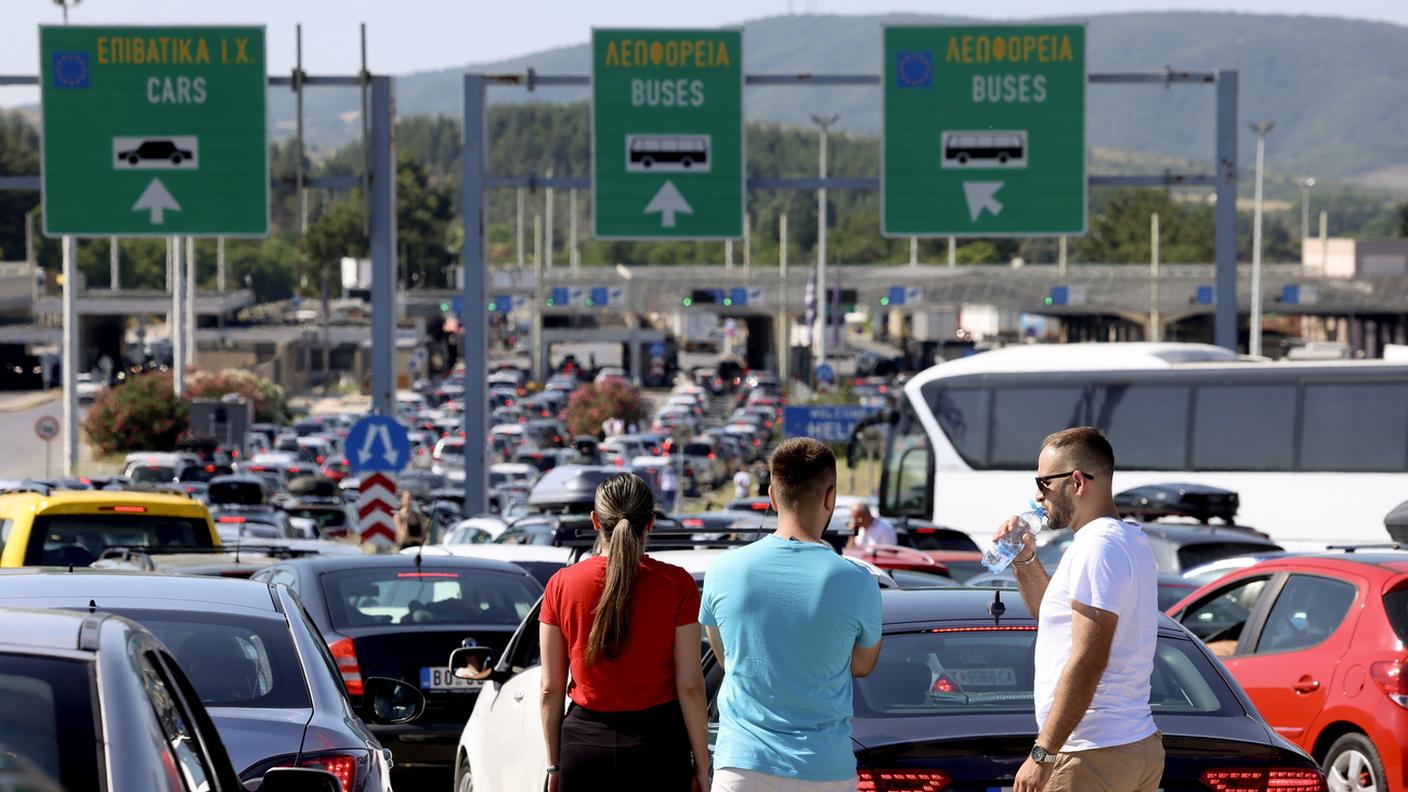 Persone in piedi accanto ai loro veicoli in attesa di entrare in Grecia