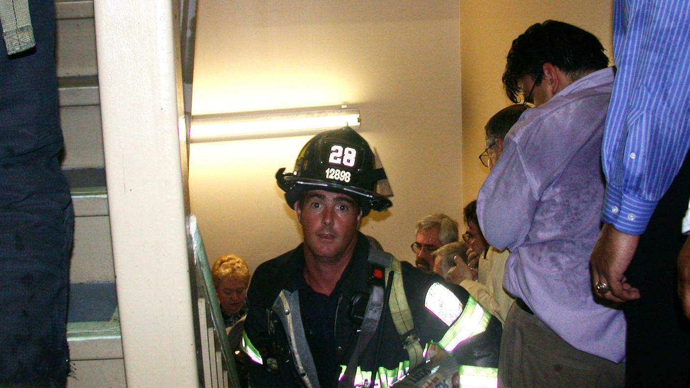 Il pompiere Mike Kehoe mentre sale le scale della Torre Nord, riuscirà a uscirne prima del crollo 