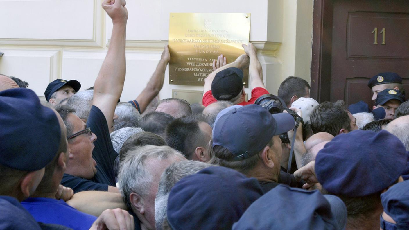 Un gruppo di manifestanti inferociti distrugge cartelli in cirillico a Vukovar
