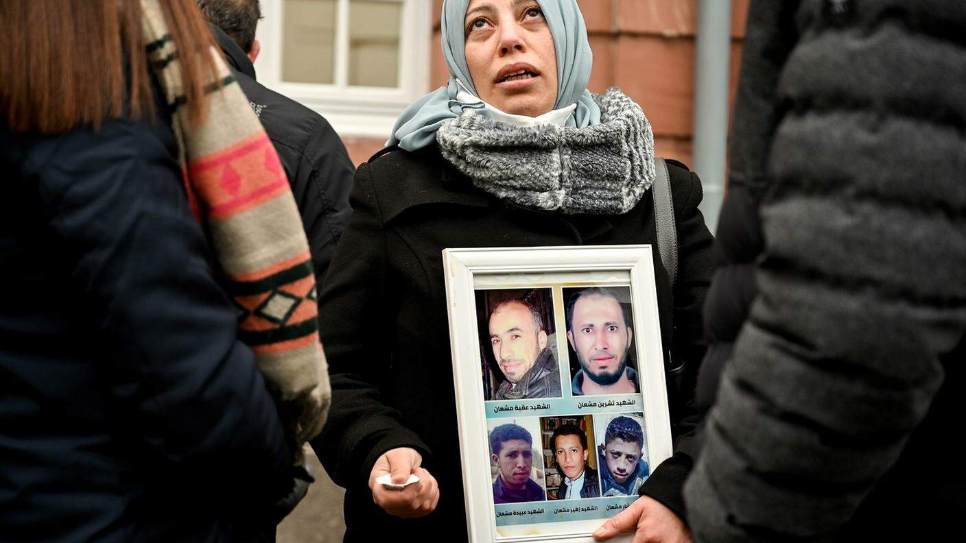 Una donna mostra la foto dei suoi fratelli uccisi in Siria davanti alla sede del tribunale