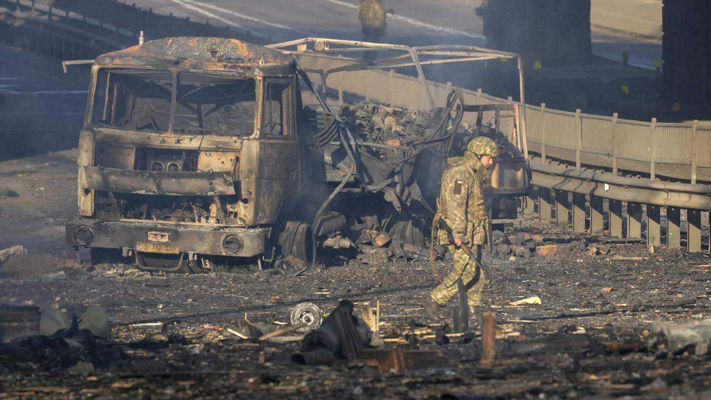 Un soldato ucraino di fronte a un veicolo militare distrutto a Kiev