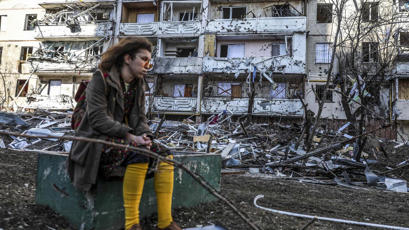 Una donna si trova accanto alle macerie di un edificio danneggiato dai bombardamenti a Kiev
